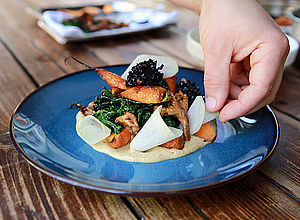 A blue plate with sea food on a table while a hand grabs a rolled slice of radish | Baltic Sea Food - a project of Interreg Baltic Sea Region (photo: toit taldrikul)