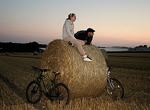 Couple sitting and leaning on a straw bale at dusk | SEMPRE - a project of Interreg Baltic Sea Region (photo: angieconscious pixelio.de)