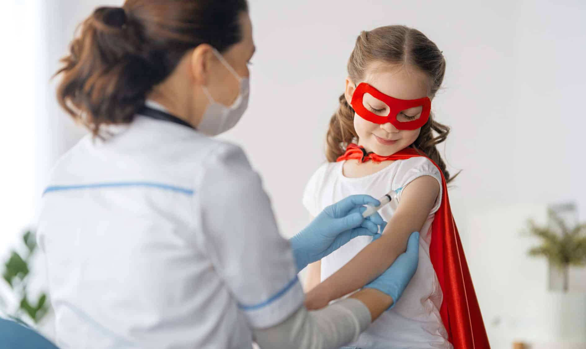 doctor vaccinating child / kid wearing a superhero costume