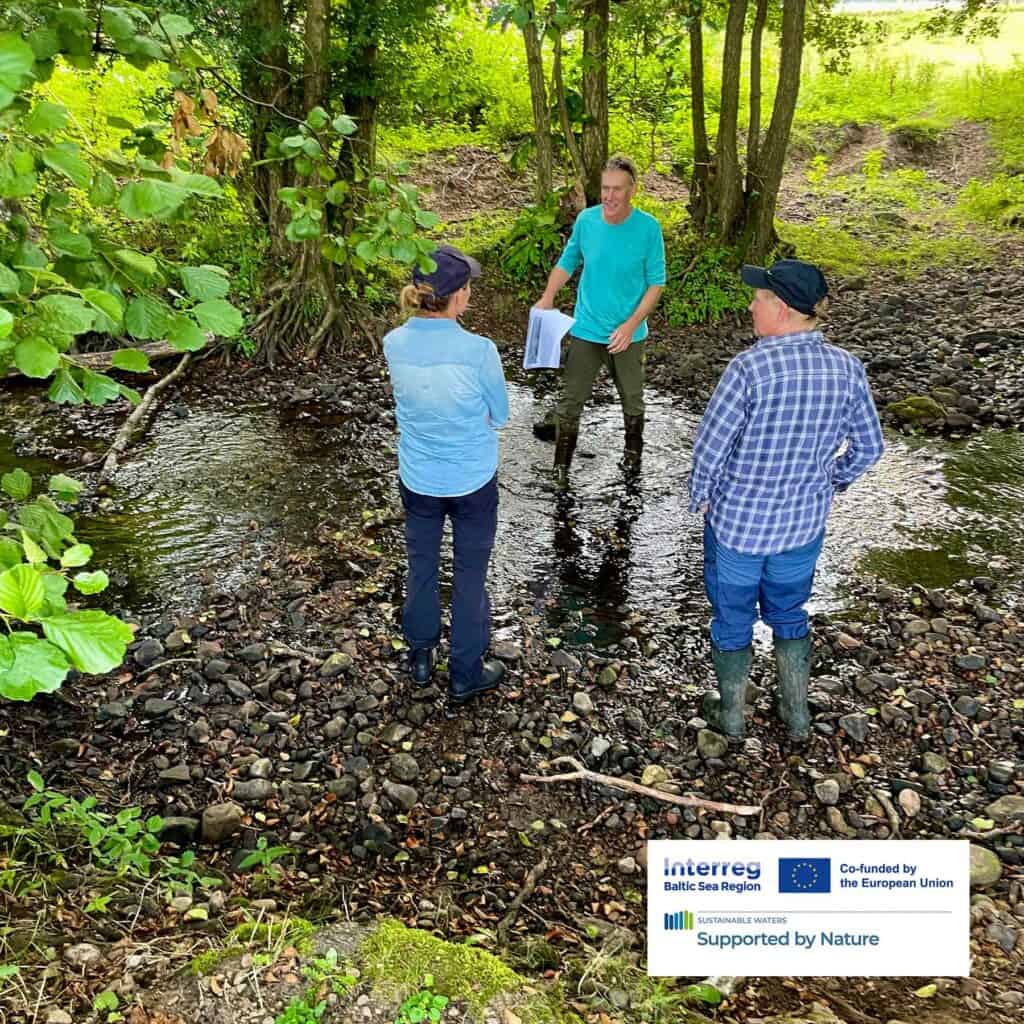 Three people is standing in water in nature surrounded by green leaf