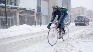 A person cycling in a snowy street.