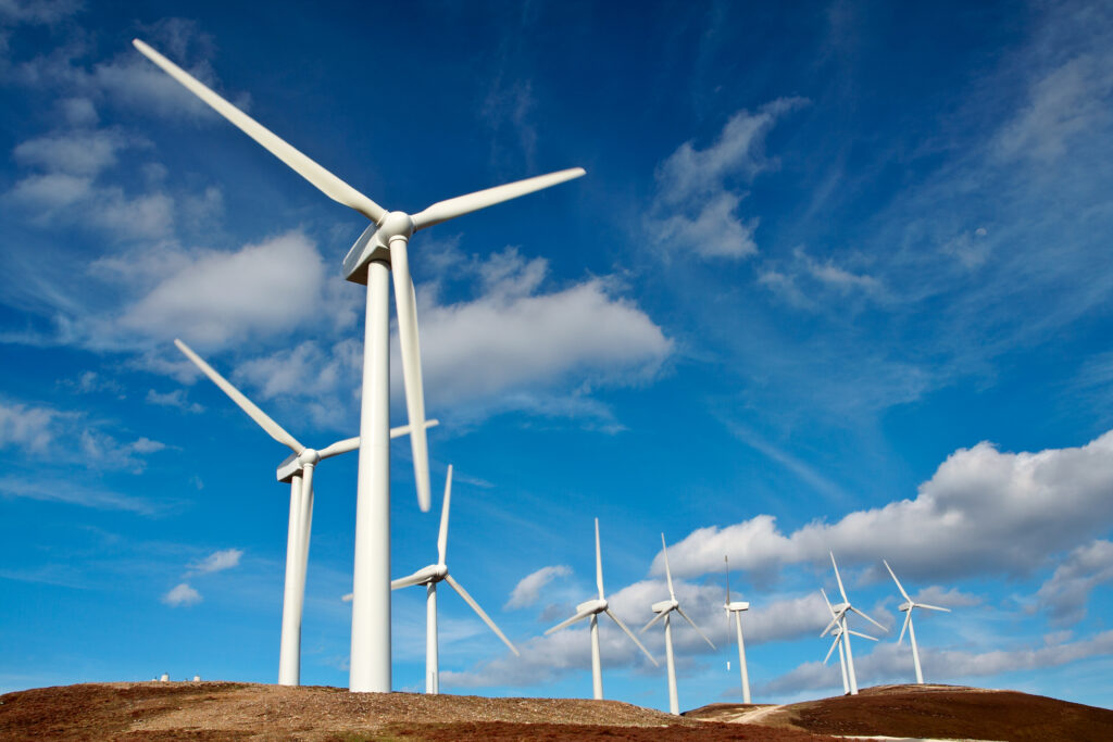Wind turbines on hill, blue sky in background